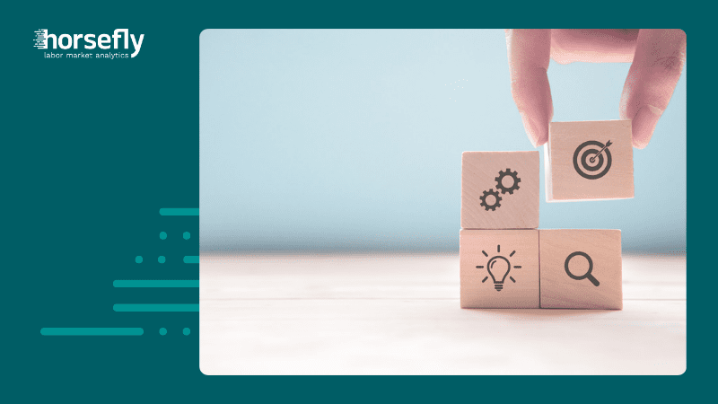 Image shows fingers holding one of four building blocks with icons for gears, lightbulb, magnifying glass and bullseye for the blog - Sharpen Your Long Game: Strategies for Effective Long-Term Workforce Planning
