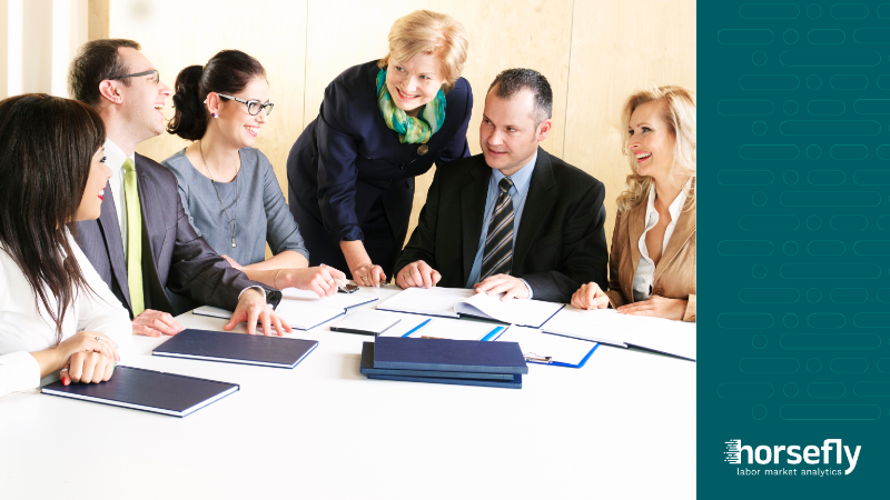 Image shows a team of colleagues working together on a project and discussing it around a table - for the blog - Workforce Data Analytics for Skills and Upskilling