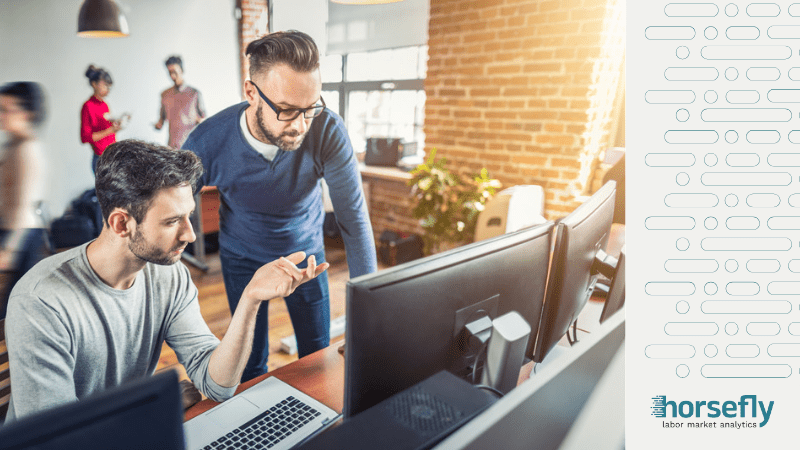 Image shows two men discussing work on a laptop for the blog - Identifying and Addressing Tech Industry Challenges with Workforce Analytics